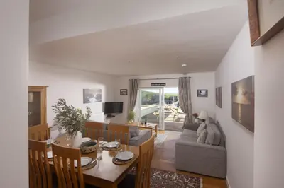 a dining room and living room with a table and a couch at 4 Glendorgal Sands, Newquay in Newquay