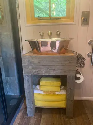 a bathroom with a sink on a table with towels at The Goose Nest luxury lakeside shepherd hut in Cardinham Woods, Cornwall in Cardinham