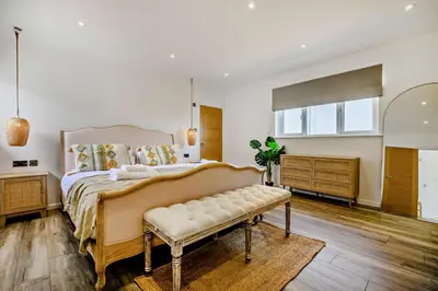 a bedroom with a large bed and a bench at 3 Bed in Downderry oc-s29364 in Downderry