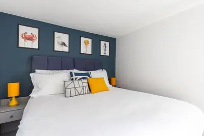 a bedroom with a white bed with a blue wall at 3 Bed in Mawgan Porth oc-s29403 in Mawgan Porth