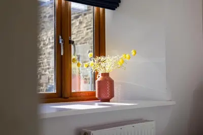 a red vase with yellow flowers sitting on a window sill at 3 Bed in Mawgan Porth oc-s29403 in Mawgan Porth