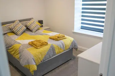 a bedroom with a bed with yellow and gray sheets at No.9 Priory House, Bodmin in Bodmin