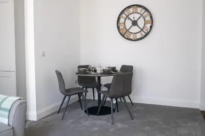 a dining room table with chairs and a clock on the wall at No.9 Priory House, Bodmin in Bodmin
