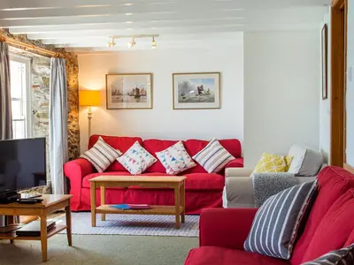 a living room with a red couch and a table at Corner Cottage - Uk47402 in Portmellon