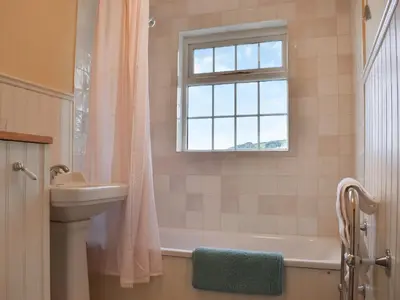 a bathroom with a tub and a sink and a window at Corner Cottage - Uk47402 in Portmellon