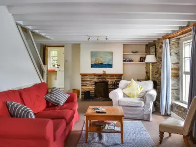 a living room with a red couch and a fireplace at Corner Cottage - Uk47402 in Portmellon