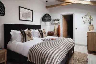 a bedroom with a large bed with a striped blanket at Kittiwake apartment - Coastal, luxury, self-catering in Port Isaac