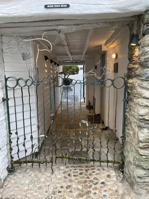 an iron gate with a peacock painted on it at Kittiwake apartment - Coastal, luxury, self-catering in Port Isaac