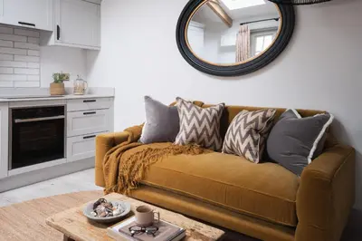 a living room with a brown couch and a mirror at Kittiwake apartment - Coastal, luxury, self-catering in Port Isaac