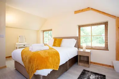 a bedroom with a large bed and two windows at Chy Lowen, Treluswell in Penryn