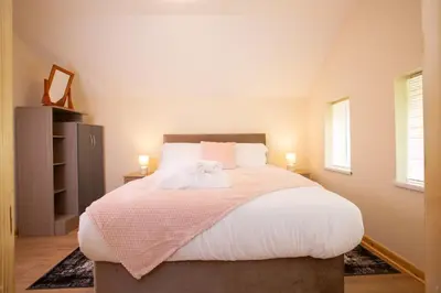 a bedroom with a large bed with a pink blanket at Chy Lowen, Treluswell in Penryn