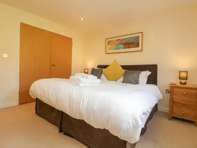 a bedroom with a large bed with white sheets at The Willows in Saint Columb Major