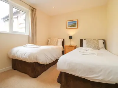 two beds in a room with a window at The Willows in Saint Columb Major