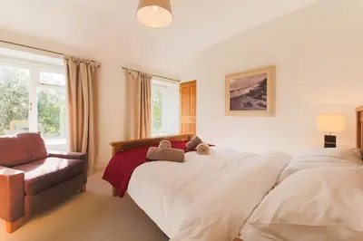 a bedroom with a large white bed and a chair at November Cottage St Kew, North Cornwall Cosy Cottage in Bodmin
