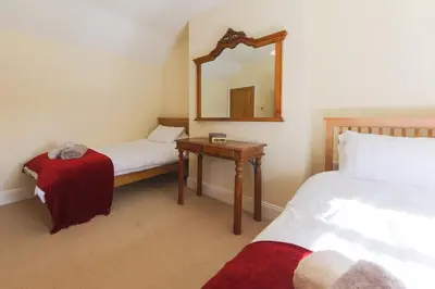 a bedroom with two beds and a table with a mirror at November Cottage St Kew, North Cornwall Cosy Cottage in Bodmin