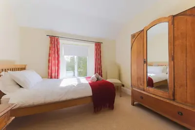 a bedroom with a large bed and a large mirror at November Cottage St Kew, North Cornwall Cosy Cottage in Bodmin