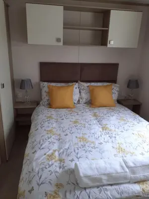 a bedroom with a large bed with yellow pillows at 2 bed 2 ensuite Holiday Home in St Austell
