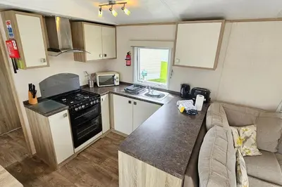 a small kitchen with a stove top oven next to a couch at 2 bed 2 ensuite Holiday Home in St Austell