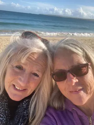 two older women sitting next to each other on the beach at Penny's Place in Carbis Bay