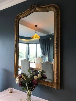 a mirror with a vase of flowers on a table at Seagulls Boutique Lodgings in Mevagissey