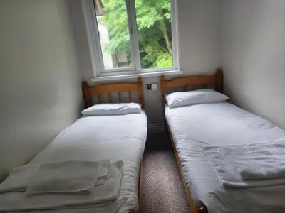 two beds in a small room with two windows at Hayle holiday cottage in Hayle