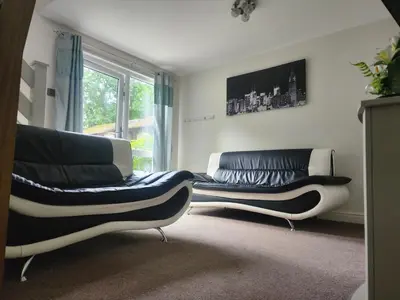 a living room with two leather couches and a window at Hayle holiday cottage in Hayle