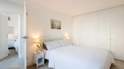a white bedroom with a white bed and white cabinets at The Lobster Pot in Port Isaac