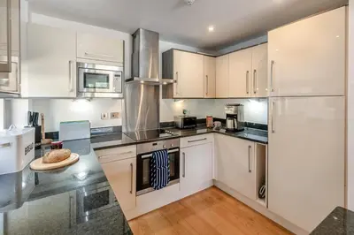 a kitchen with white cabinets and stainless steel appliances at 2 Bed in Looe oc-n29477 in Looe