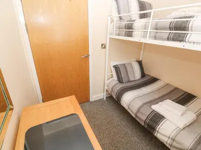 a small room with a bunk bed and a desk at Greenwood Apartment in St Ives
