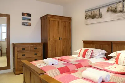 a bedroom with two beds and a dresser at Porthminster View Luxury Sea Views Balcony, Parking, Pool, Spa & Gym in St Ives