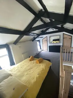 a bedroom with a yellow bed in a attic at Bumblebee Cottage in Redruth