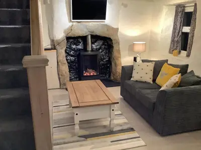 a living room with a couch and a fireplace at Bumblebee Cottage in Redruth
