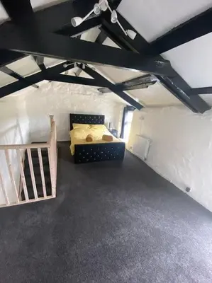 a room with a bed and a staircase at Bumblebee Cottage in Redruth