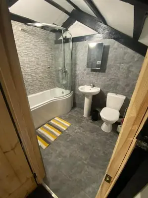 a bathroom with a tub and a toilet and a sink at Bumblebee Cottage in Redruth