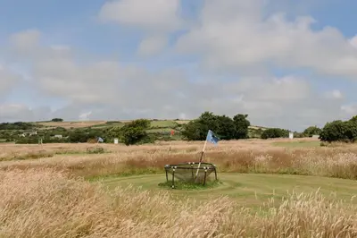 a bench in a field with a blue flag at Wheal Prosper - Hot Tub - Free Wi-Fi - Parking - On-site Activities in Helston