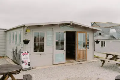 a small white building with a door and a picnic table at Wheal Prosper - Hot Tub - Free Wi-Fi - Parking - On-site Activities in Helston