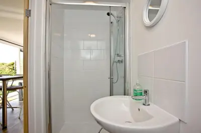 a white bathroom with a sink and a shower at Wheal Prosper - Hot Tub - Free Wi-Fi - Parking - On-site Activities in Helston