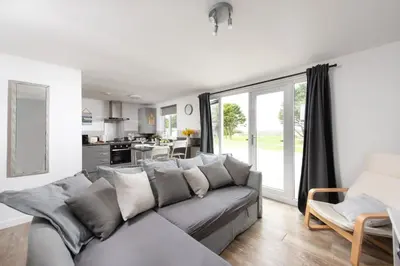 a living room with a gray couch and a kitchen at Wheal Prosper - Hot Tub - Free Wi-Fi - Parking - On-site Activities in Helston