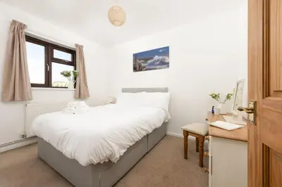 a bedroom with a bed with white sheets and a window at Wheal Francis - Hot Tub - Accessible Bungalow - Free Wi-Fi - Parking in Helston