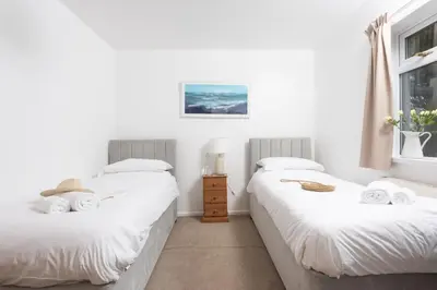two beds in a room with white walls and a window at Wheal Francis - Hot Tub - Accessible Bungalow - Free Wi-Fi - Parking in Helston
