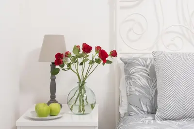 a vase with roses on a table next to a bed at Wheal Jewel - Hot Tub - On-site Activities - Free WiFi - Parking in Helston
