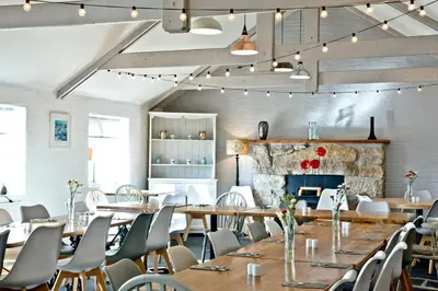a dining room with tables and chairs and a fireplace at Wheal Jewel - Hot Tub - On-site Activities - Free WiFi - Parking in Helston