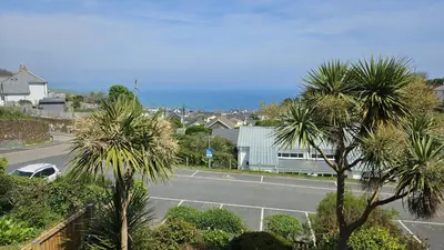 a tennis court with palm trees in a town at Chywartha in Porthscatho