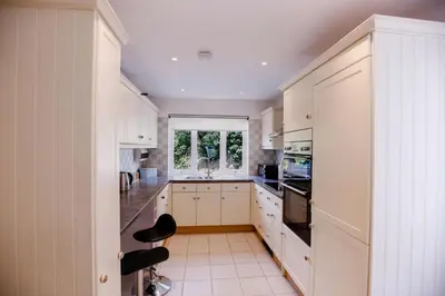 a kitchen with white cabinets and a window at St Anthony Cottage in Saint Mawes