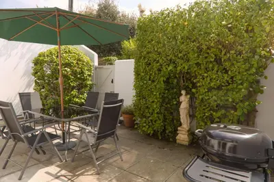 a grill and a table and chairs with an umbrella at St Anthony Cottage in Saint Mawes