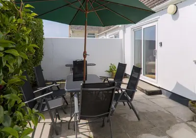 a table and chairs with an umbrella on a patio at St Anthony Cottage in Saint Mawes