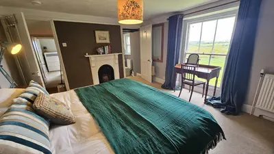 a bedroom with a bed and a fireplace and a desk at Tregongon House in Veryan