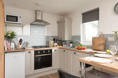 a kitchen with white cabinets and a black oven at Bushwood - Free WiFi - Parking - Pet Friendly - On-site Activities in Helston
