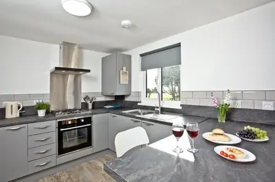 a kitchen with a table with two glasses of wine at Wheal Rose - Hot Tub - Parking - Free WiFi - On-Site Activities in Helston