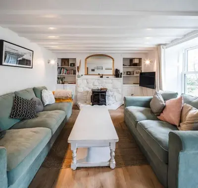 a living room with two couches and a fireplace at Charming Cottage near Beach! in Redruth